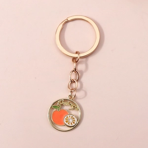 Vue détaillée du porte-clés en alliage doré avec orange émaillée et design cercle ajouré
