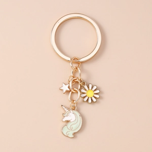 Detail eines goldenen Schlüsselanhängers mit Stern, Gänseblümchen und Einhorn-Anhänger