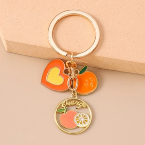 Detail view of golden orange fruit keychain with heart charm and leaf decor