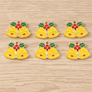 Detailed view of six DIY Christmas bell pendants with holly leaves on light wood surface
