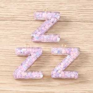 Detail of purple resin Z-shaped pendants with holographic star sequins and gold rings