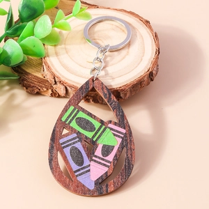 Detail of wooden teardrop keychain with colorful crayons on a natural wood slice