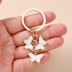 Porte-clés papillon chic avec trois pendentifs en émail blanc sur anneau doré pour sacs