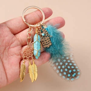 Bohemian dreamcatcher keychain with turquoise hexagonal pillar and feathers held by hand