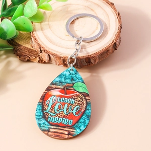 Detail of wooden teardrop keychain with Teach Love Inspire apple design on tree stump