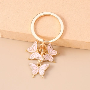 Détail macro d'un porte-clés papillon doré avec trois pendentifs en émail rose