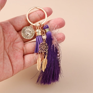 Detailed view of a purple tassel keychain with gold coin and dreamcatcher feather