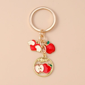 Detail of gold keychain set featuring heart and apple enamel charms with Apple text