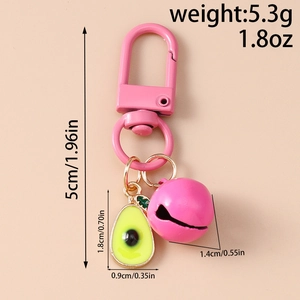 Detailed view of pink bell and avocado pendant keychain on a pink solid background