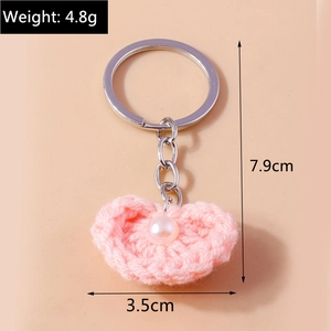 Makro-Detail des rosa gehäkelten Herz-Schlüsselanhängers mit Perle und Silberring