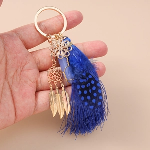 Detailed close-up of a blue feather dreamcatcher keychain with gold accents and tassels