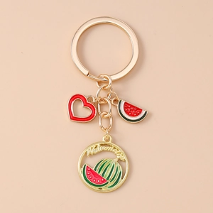 Detail of golden watermelon keychain featuring red heart charm and vibrant enamel pendants