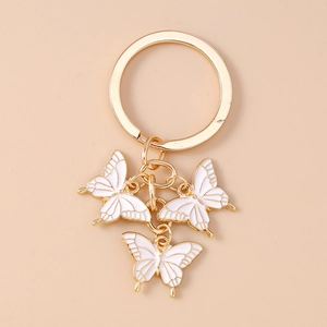 Détail du porte-clés doré orné de trois élégants pendentifs papillon en émail blanc