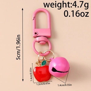 Detail of red apple charm keychain with pink bell and dimensions in centimeters and inches