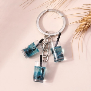 Detail von drei blauen Miniatur-Milchtee-Anhängern mit Glitzerflüssigkeit und Silberring