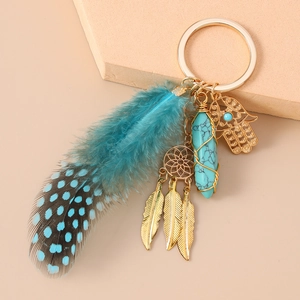Detail of dreamcatcher keychain with blue feather, crystal pillar and golden charms