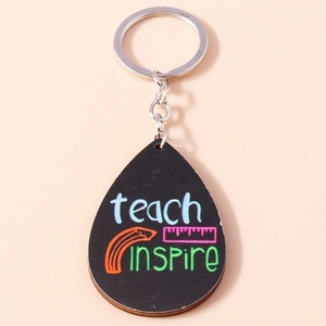 Macro view of teardrop wooden keychain with Teach Inspire lettering and pencil motifs