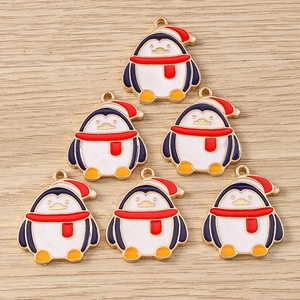 Detail view of penguin alloy enamel charms for Christmas jewelry DIY on wood background