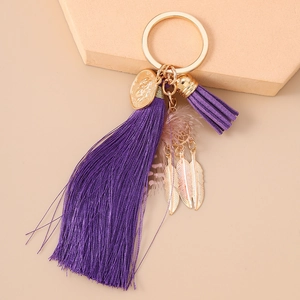 Detail view of purple tassels and gold feather charms on a bohemian dreamcatcher keychain