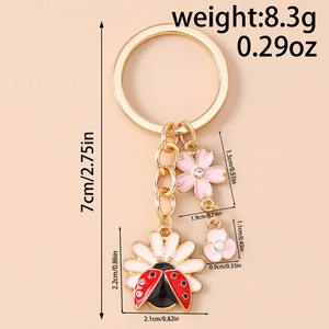 Detail view showing dimensions of floral daisy and ladybug keychain in golden finish