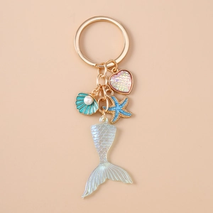 Detail of mermaid tail keychain with blue star and pearl shell on pink background