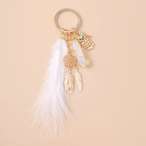 Detail view of gold dreamcatcher keychain with white feather and crystal pillar pendant