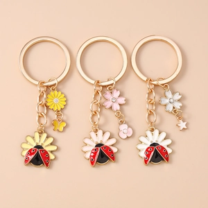 Close-up of golden keychain sets with ladybug charms and colorful daisy flower details
