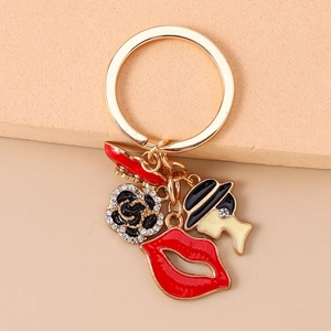 Detail of gold keychain with red lips, rose, and rhinestone lady charms for bags