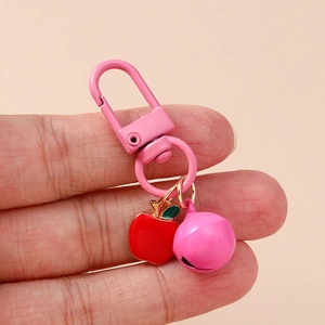 Detail of a pink apple keychain with metal lobster clasp and matching bell ornament