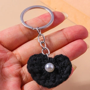 Detail eines schwarzen gestrickten Herz-Schlüsselanhängers mit Perle und silbernem Ring