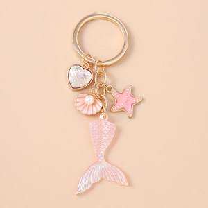 Detailed close-up of a golden mermaid tail keychain with heart and shell charms