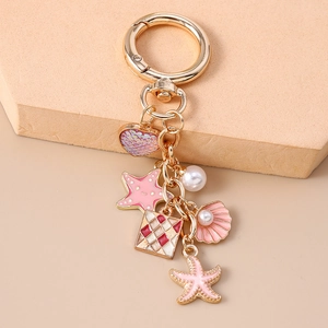 Detail of golden ocean-themed keychain with enamel starfish, shell and pearl charms