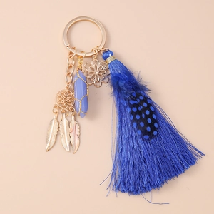 Detail view of bohemian keychain with purple crystal and blue silk tassel on pink background