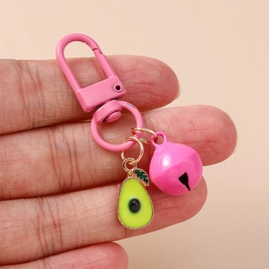 Macro detail of avocado charm keychain with pink bell and lobster clasp on hand