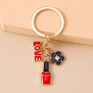 Detail of gold keychain with red LOVE charm, floral pendant and lipstick accessory