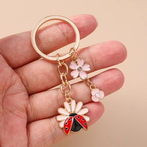 Floral ladybug keychain with daisy charm and pink flower pendants in rose gold finish