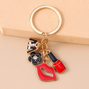 Detail of red lips, lipstick, flower and clothing charms on gold keychain accessory