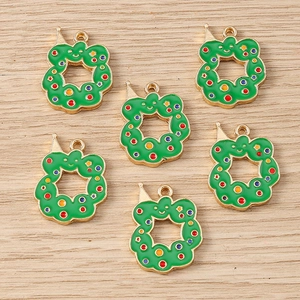 Detailed view of DIY Christmas wreath charms with colorful enamel dots on a wood surface