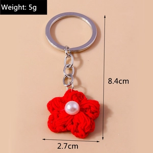 Detailed close-up of a red crochet flower keychain with a white pearl and silver ring
