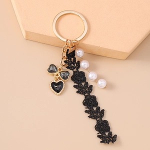 Detail of fashion keychain with black lace ribbon, pearl beads and gold heart charm