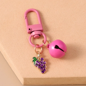 Detail of pink metal clasp and purple grape enamel charm on a bell keychain