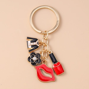 Detail of gold keychain featuring enamel jacket, black camellia flower, and red lips charms