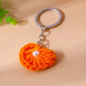 Nahaufnahme von orangefarbenem Häkel-Muschel-Schlüsselanhänger mit Perle und Metallring