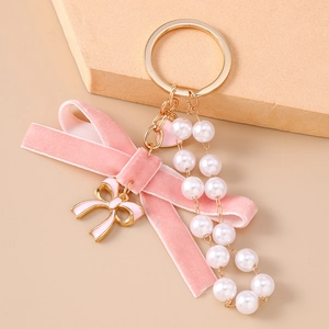 Detailed shot of pink velvet bow keychain with pearl tassels and golden keyring