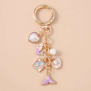 Detail of golden mermaid tail keychain with pink shell charms and pearl heart accents