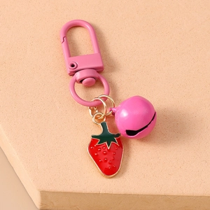 Close-up of pink bell and red enamel strawberry pendant with pink metal carabiner clip
