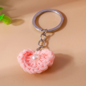 Detailansicht handgefertigter rosa Häkel-Herzanhänger mit Perle und silbernem Schlüsselring