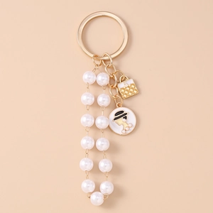 Detail of fashion keychain with pearl tassels, golden bag charm and lady profile pendant