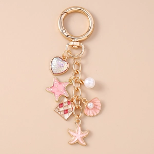 Detail of a golden shell and starfish keychain with heart pendant and white pearls
