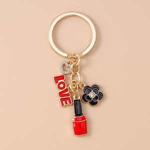 Detail of gold metal keychain featuring enamel LOVE charm, heart, flower, and lipstick charm